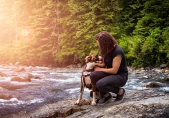 boxer on hike next to stream with owner