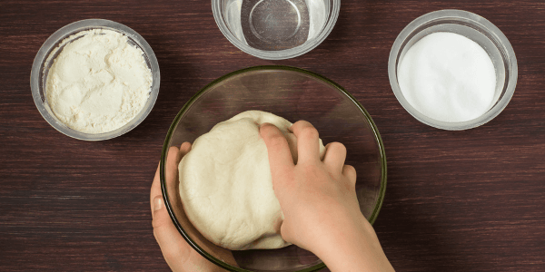 childs hands kneading dough in a bowl