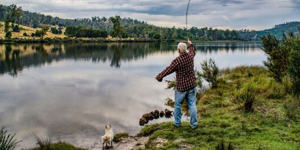 little white dog on the shore with a man who is fishing-canva 