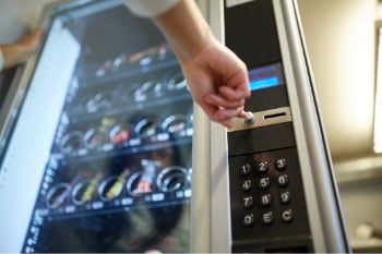 womans hand pushing button on snack vending machine