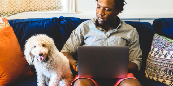 man on computer with his dog sitting next to him 